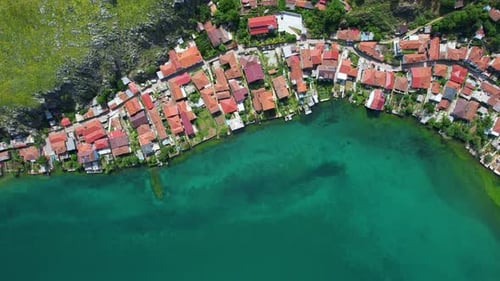 Red-Roofed Houses by the Emerald Lake: Drone View of the Serene Touristic Village Beneath the Beauti