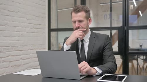 Pensive Middle Aged Businessman Working on Laptop