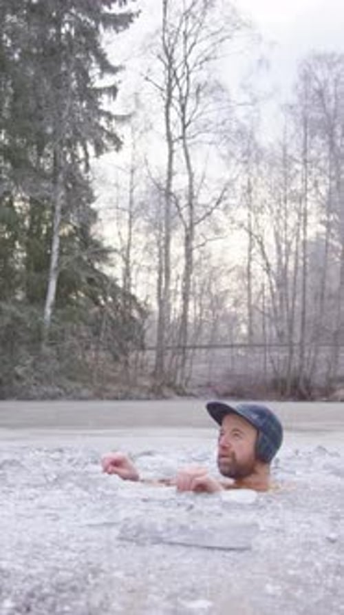 Plan hilarant d'un baigneur de glace assis dans un lac suédois gelé, à la verticale