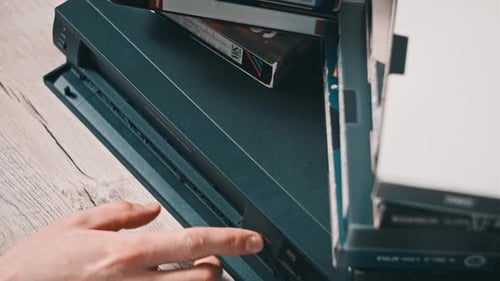 Hand Inserts VHS Tape Into VCR Player