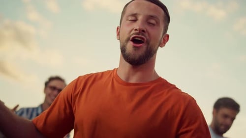 Man Singing with Friends at Sunset Celebration