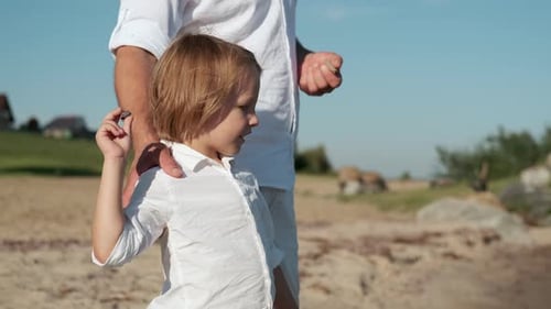 Father and Son Throw Stones Into the Water From the Ocean