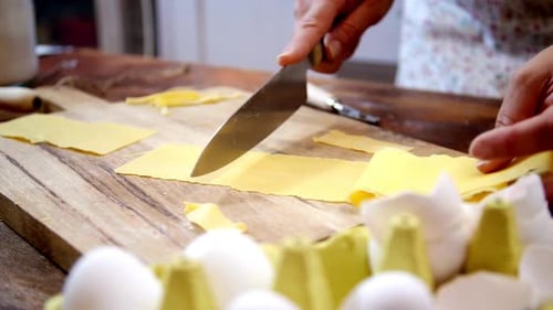 Woman Cuts Pasta Dough on Wooden Cutting Board