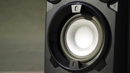 close up zooming in on a speaker blasting out music bass creating shake of the disk inside the plast