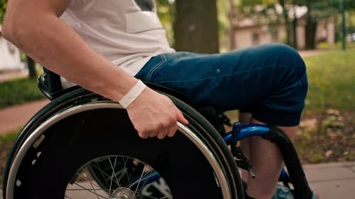 A man performs tricks on a wheelchair in a city park active lifestyle recreation close-up of hands