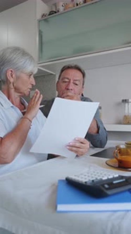Couple Reviewing Paperwork at Kitchen Table