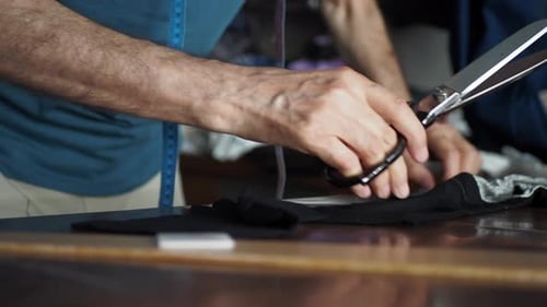 Adult Hands Cutting Black Fabric with Tailoring Scissors
