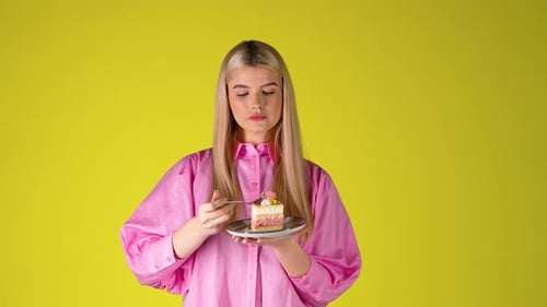 Pretty Young Blonde Woman Eating Delicious Cake, Studio Portrait With Yellow Background