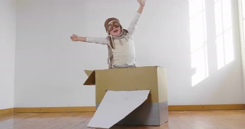 Ein als Flieger oder Pilot verkleidetes Mädchen im Schlafzimmer tut so, als würde es ein Papierflugzeug fahren und stellt sich vor