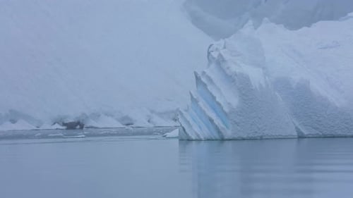 Riesiger Eisberg, der im kalten Meerwasser an der schneebedeckten Küste der Antarktis schwimmt