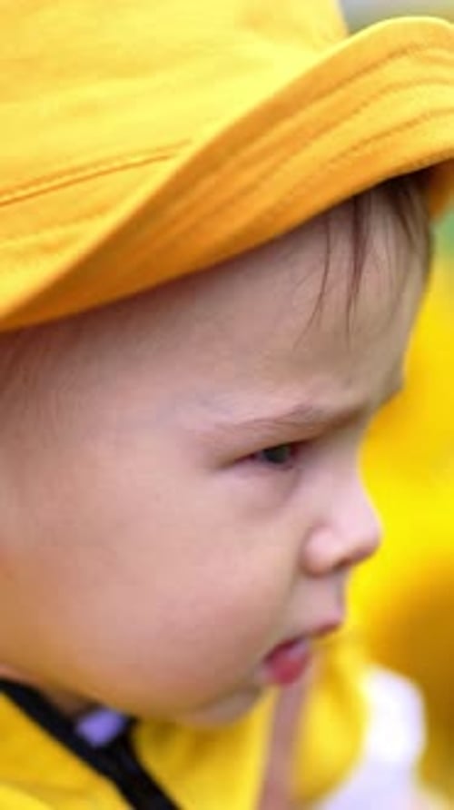 Serious focused little boy in yellow panama looking intently somewhere. Close up portrait.