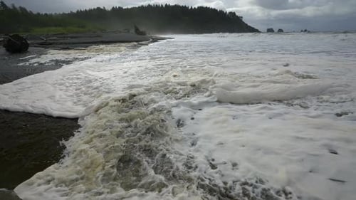 Rolling Waves With Sea Foams Through The Shoreline Of A Beach. Close Up