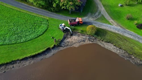 Trabalhos aéreos sobre escavadeiras ao lado de um lago, arredores de construção, paisagem de campos verdes