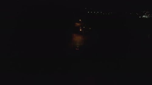 Mysterious aerial tracking shot, following car into dark woods at night, suspense, thriller theme