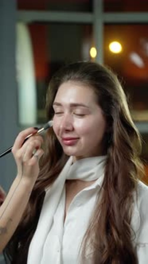 Woman Having Makeup Applied with Brush Indoors