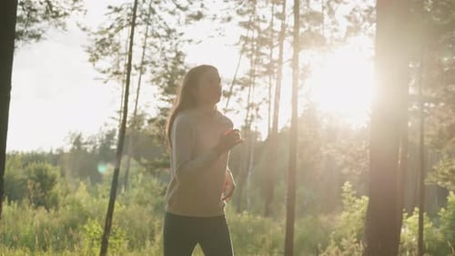 Woman Athlete Runs in Woods at Sunset