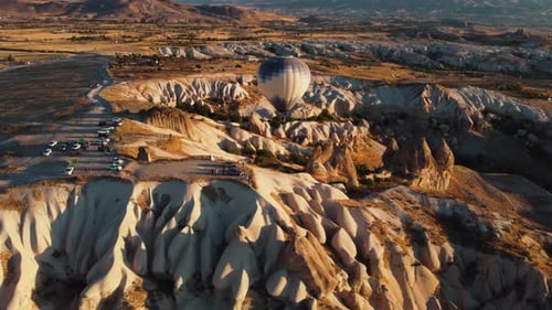 balloon going over the cliff in Love valley Cappadocia in Turkey with people spectating from the