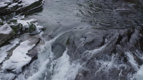 Río que fluye a través de las rocas y más abajo y las piedras sobre el agua están cubiertas de