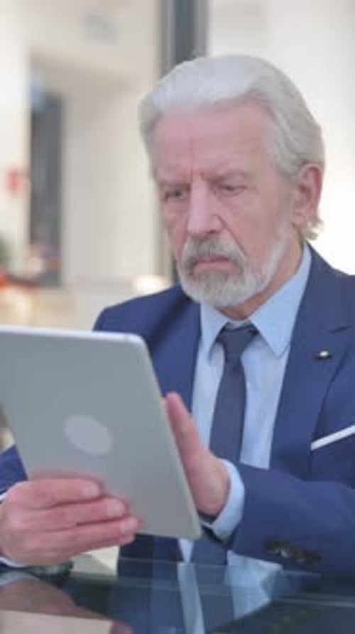 Mature Man Uses Tablet Device in Office Environment