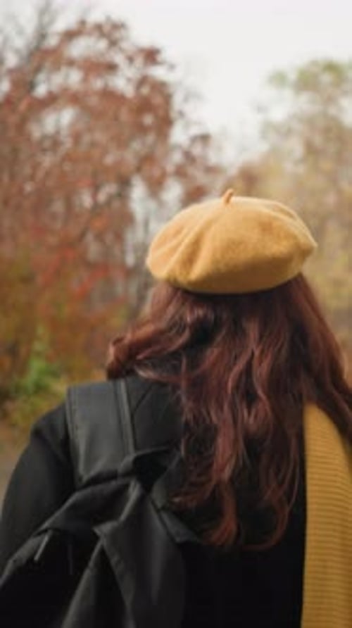Back View of Lady Strolling Through Autumn Forest with Yellow Beret and Muffler