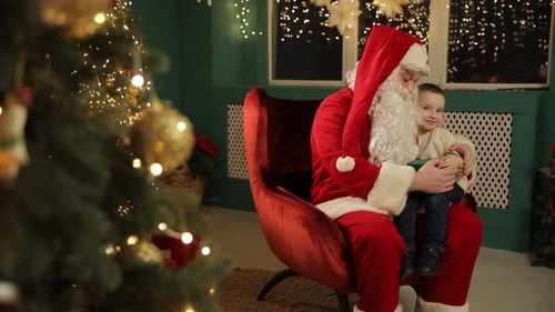 Boy with Santa Claus Holding Gift by Christmas Tree