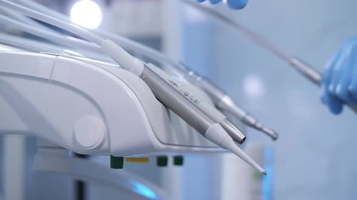 Dentist Picking Up Dental Drill for Teeth Treatment in Clinic