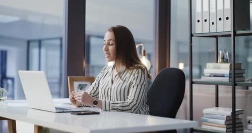 4k video footage of a young woman using a laptop to make a video call in a modern office