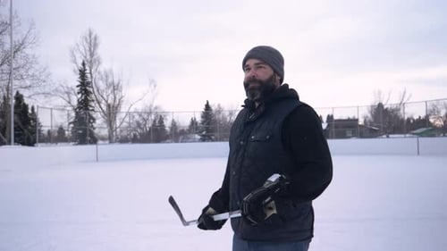 Handsome Man with Hockey Stick on Winter Ice Rink Adult
