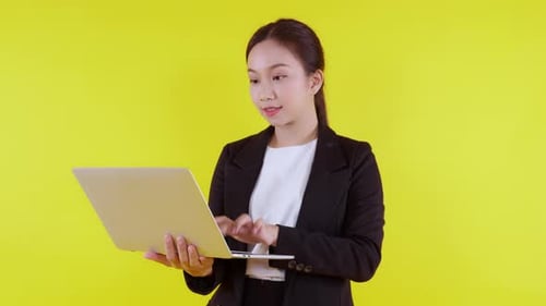 Woman Celebrates Success With Laptop in Studio