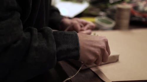 Hands Tying Twine Around Wrapped Gift