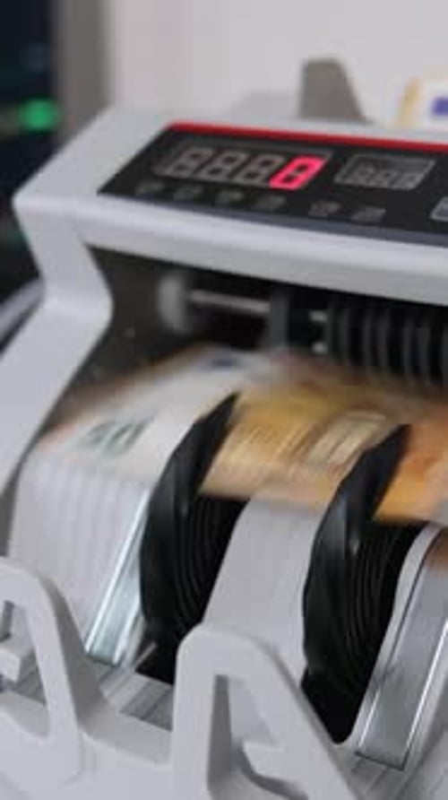 Money counting machine with a wad of fifty euro banknotes. Close up.