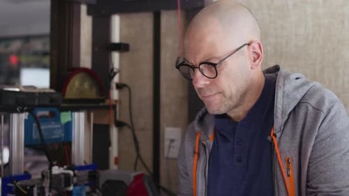 Man Works with Tablet near 3D Printer