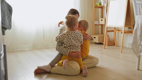 Woman Sitting With Affectionate Children Indoors