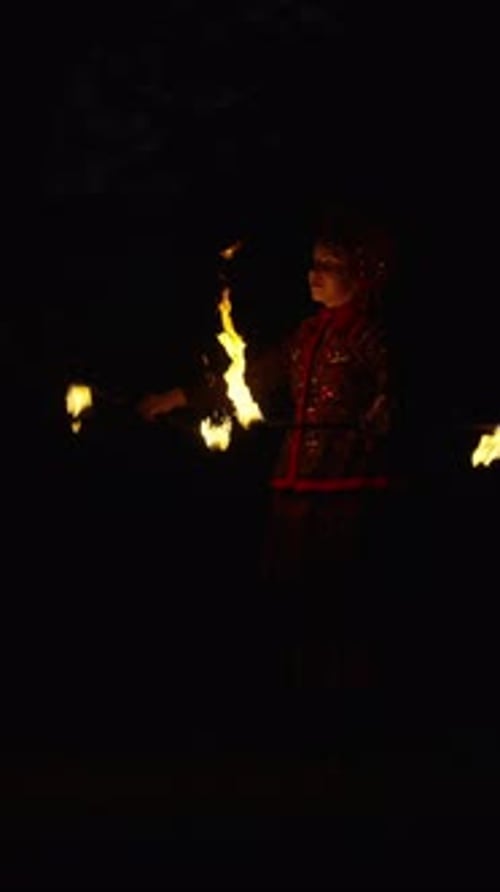Nighttime Fire Performance with Skilled Jugglers Spinning Flaming Batons in Dramatic Darkness