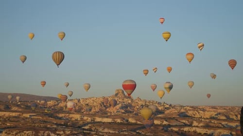 Sky filled with hot air balloons drifting over the dry landscape of Cappadocia, Turkey. Festival of