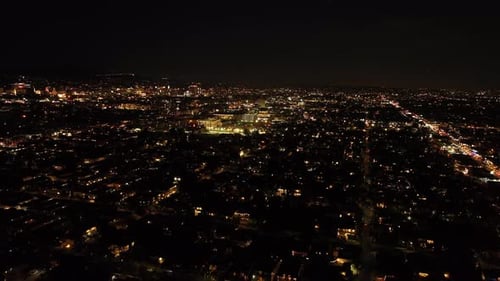 Forwards Fly Above Large City at Night Buildings and Streets in Urban Neighbourhood