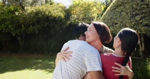 Family hugging and smiling together in garden, enjoying outdoor time