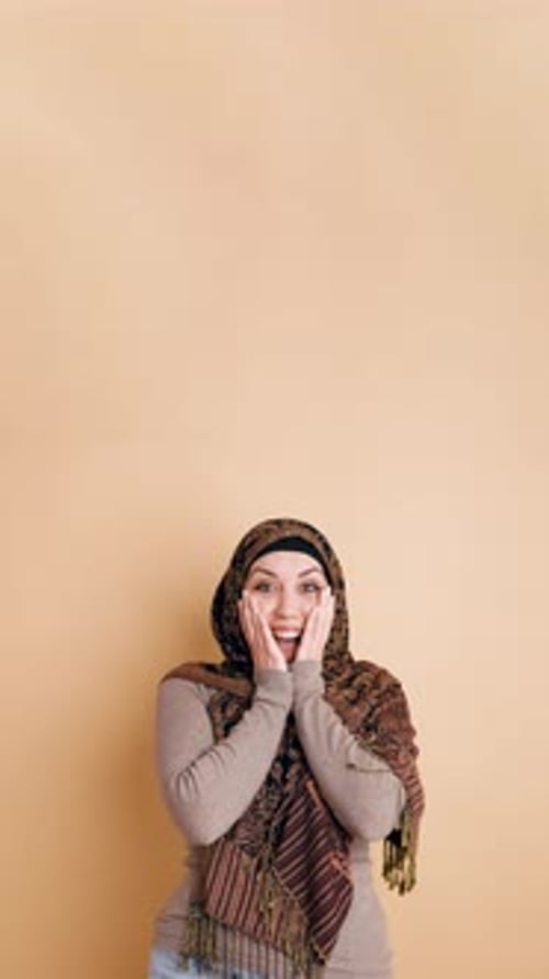 Überraschte muslimische Frau im Hijab zeigt vertikale Emotionen