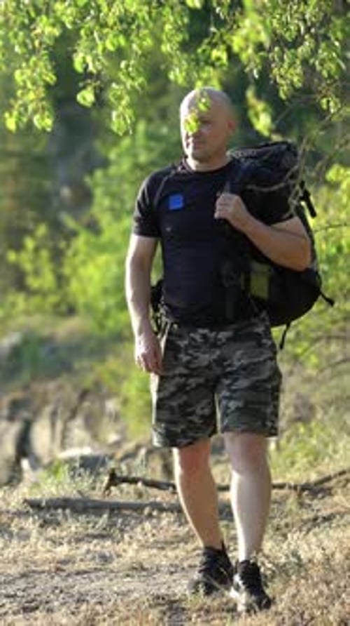 Aerial view of a young traveler with a backpack walking along a rocky path. Camping season.
