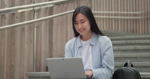 Young Woman Using Laptop on Concrete Steps