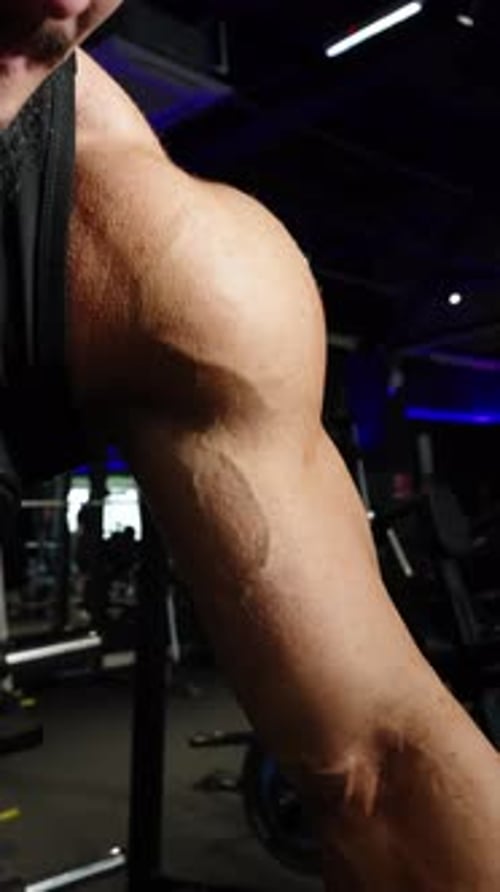 Closeup of a Muscular Arm Gripping a Metal Bar During an Intense Strength Workout Showcasing