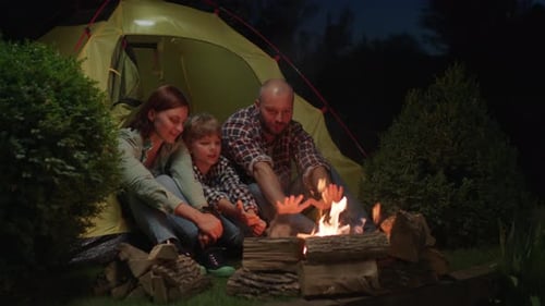 Family with Kid Talking Sitting in Tent By Campfire at Night Evening Camping Fire Talk Mom Dad and
