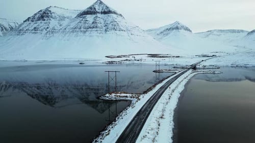 Scenic Road With Snowy Peaks Reflected In Lake