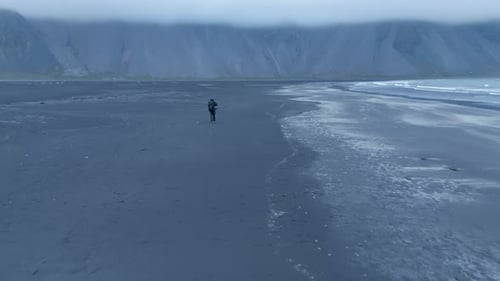 Drone Fly Over Lone Man Walking On Stokksnes Seashore Near Vestrahorn Mountain In Iceland. Aerial Sh