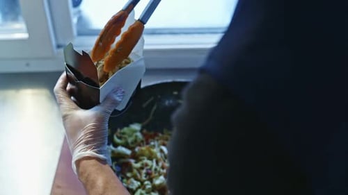 Chef Filling Take Out Container with Chow Mein