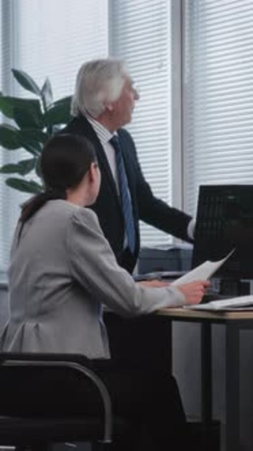 Man Discussing Documents with Colleague in Office