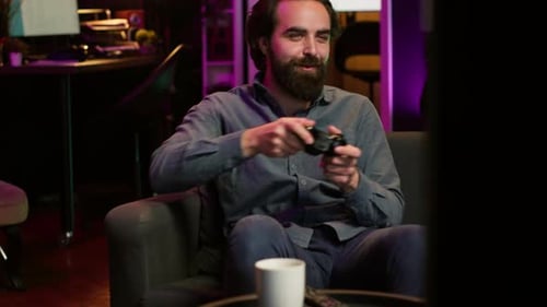 Homme appréciant de jouer à un jeu vidéo dans une pièce éclairée au néon tenant une manette
