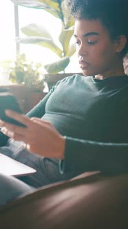 Young Woman Uses Phone While Sitting on Couch