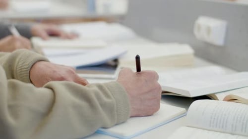 Unerkennbarer älterer Mann, der eine Gliederung in ein Notizbuch schreibt