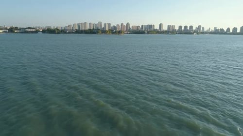 Aerial View Lake Water Surface on Sunset Cityscape on the Background